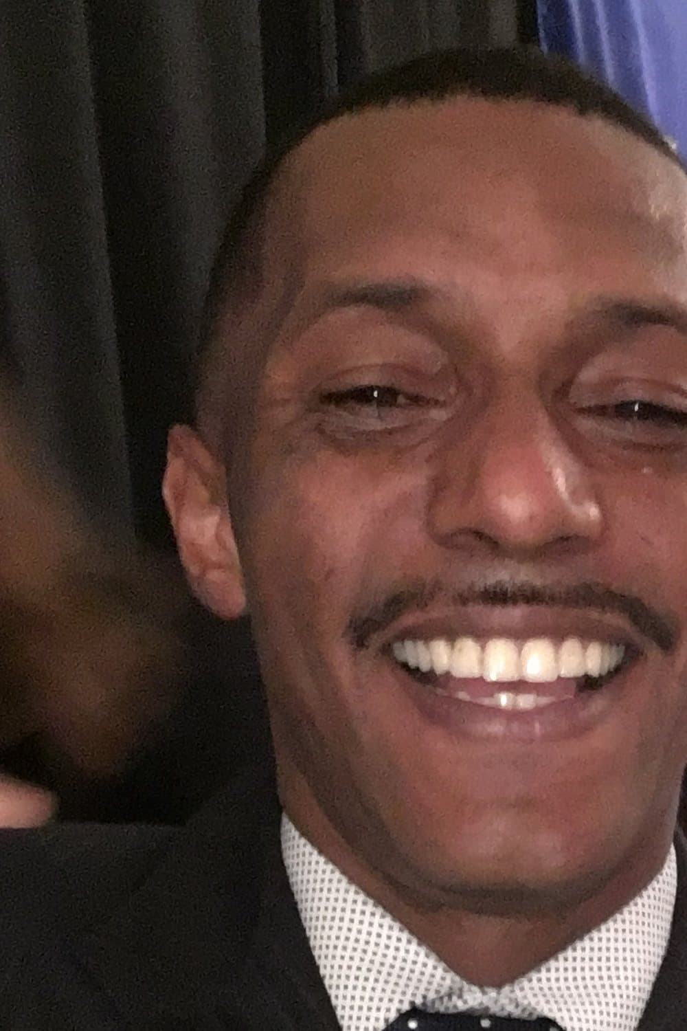 Deonte in a dark pinstripe suit and polka-dot tie, grinning