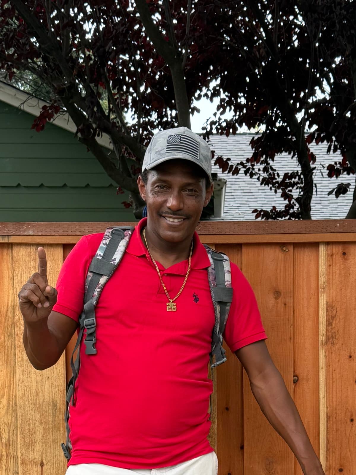 Deonte smiling in a red polo and a gray cap